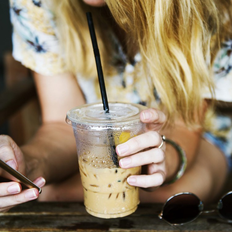 Mobile-Shopping der neue Trend Junge Frau die gerade einen Smoothie genießt und auf Ihrem Smartphone shoppt